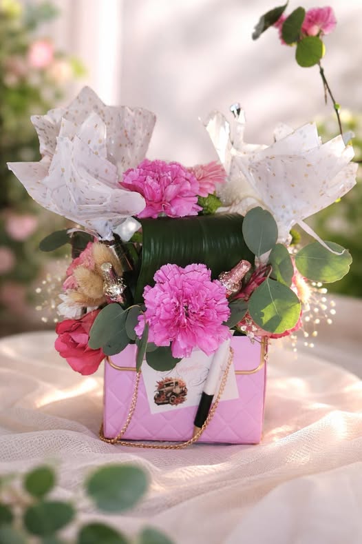 Création florale présentée dans un sac à main rose